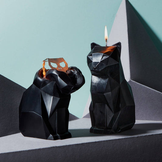 A black cat-shaped candle with a metallic skeleton design inside, partially melted to reveal the skeleton