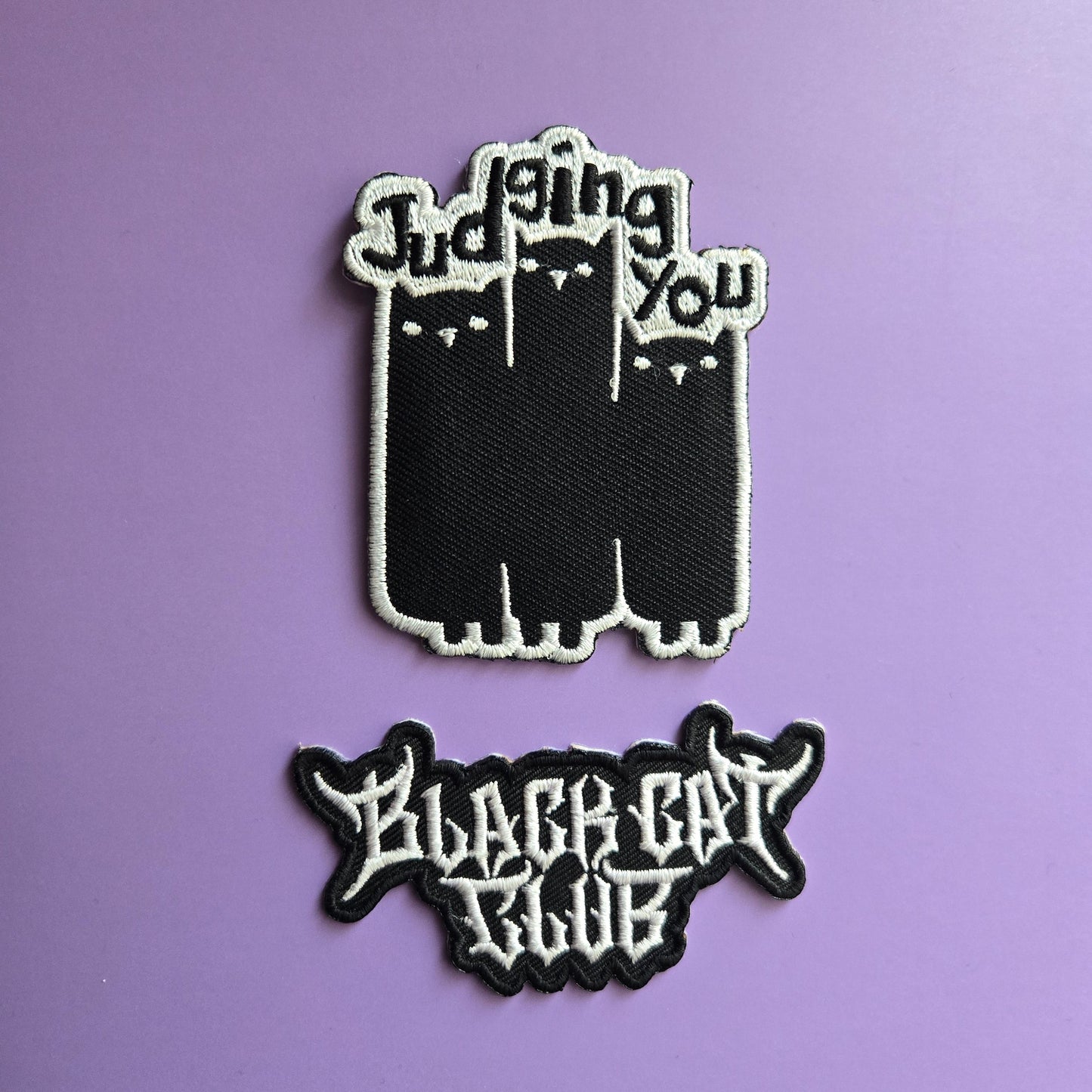 Two black patches with white text on a purple background