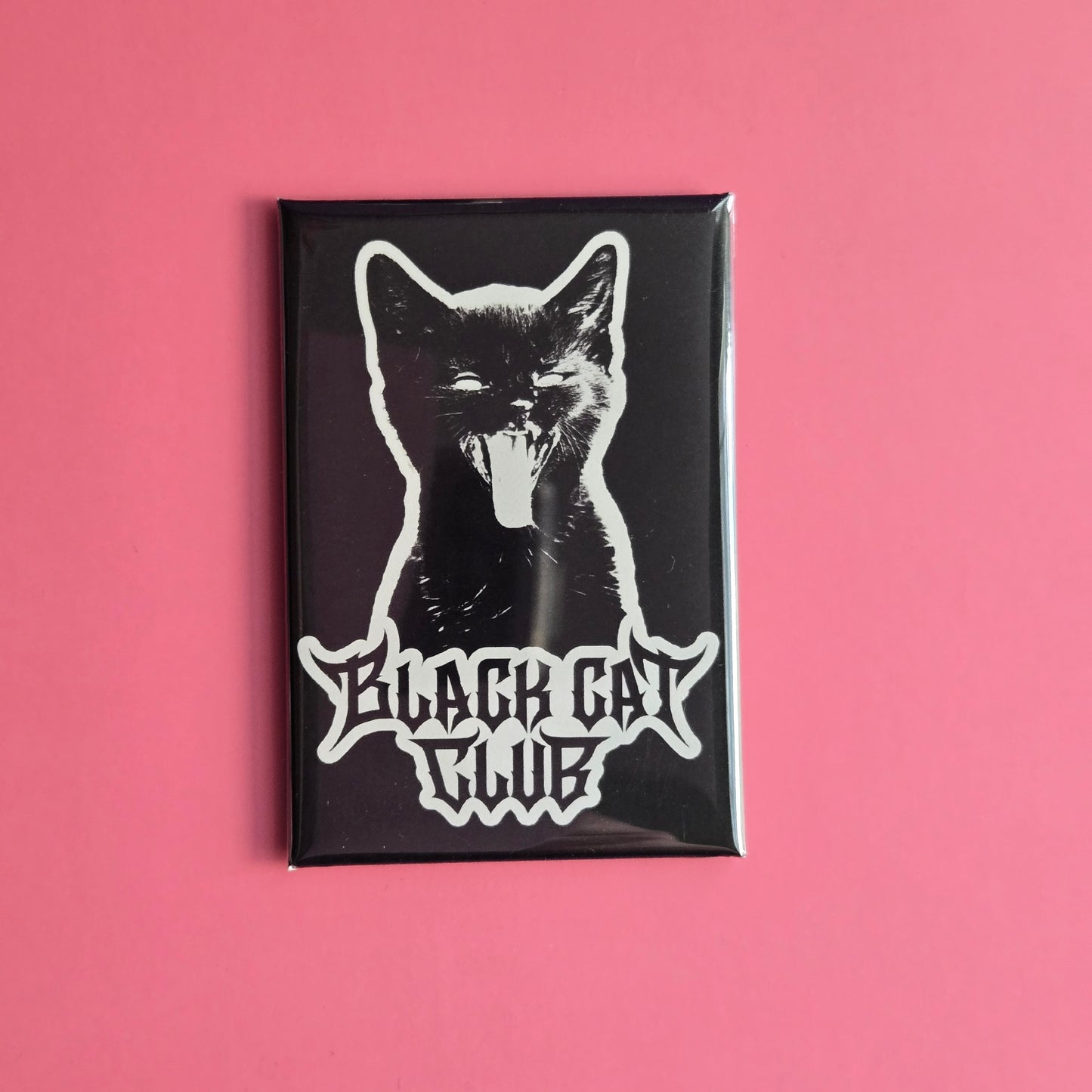 A fridge magnet featuring a white silhouette of a hissing kitten with the text 'Black Cat Club'