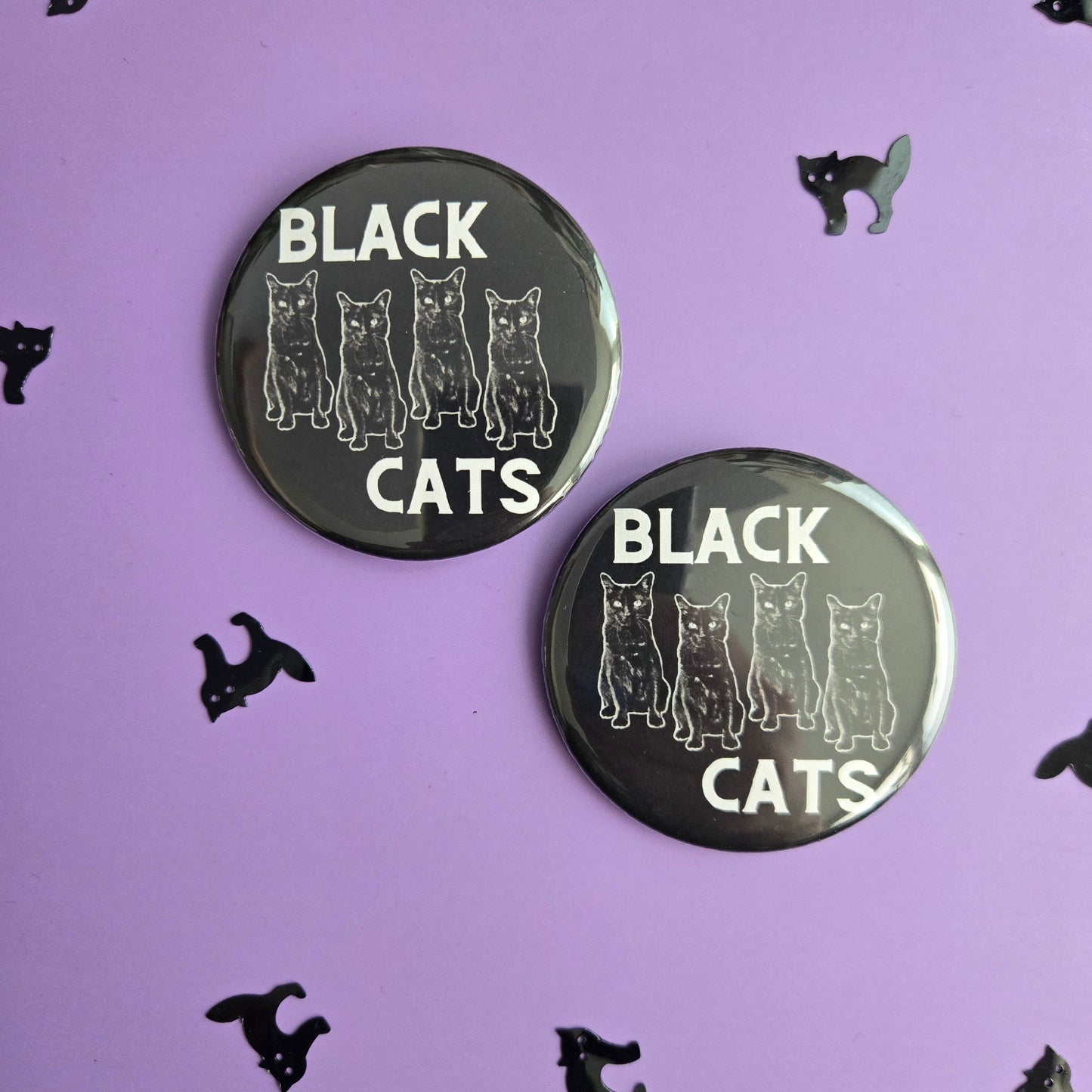 Two black buttons with 'BLACK CATS' text on a black background with small black cat illustrations.