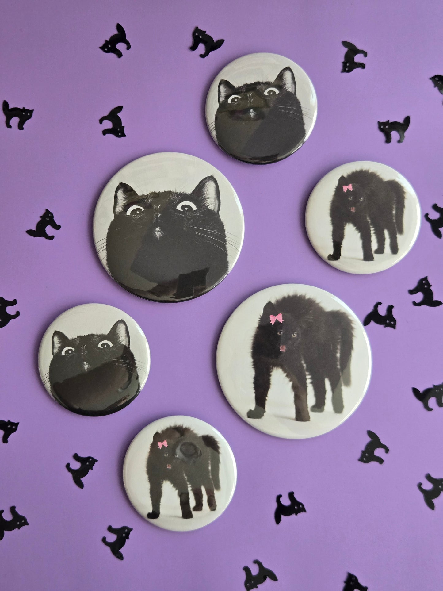 Set of six circular magnets and buttons with black cat illustrations on a purple background.