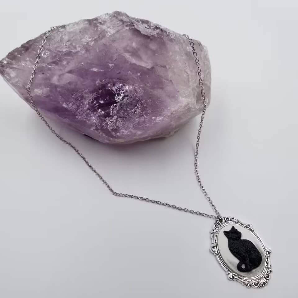 Cameo necklace with a black cat design on a white background and silver chain