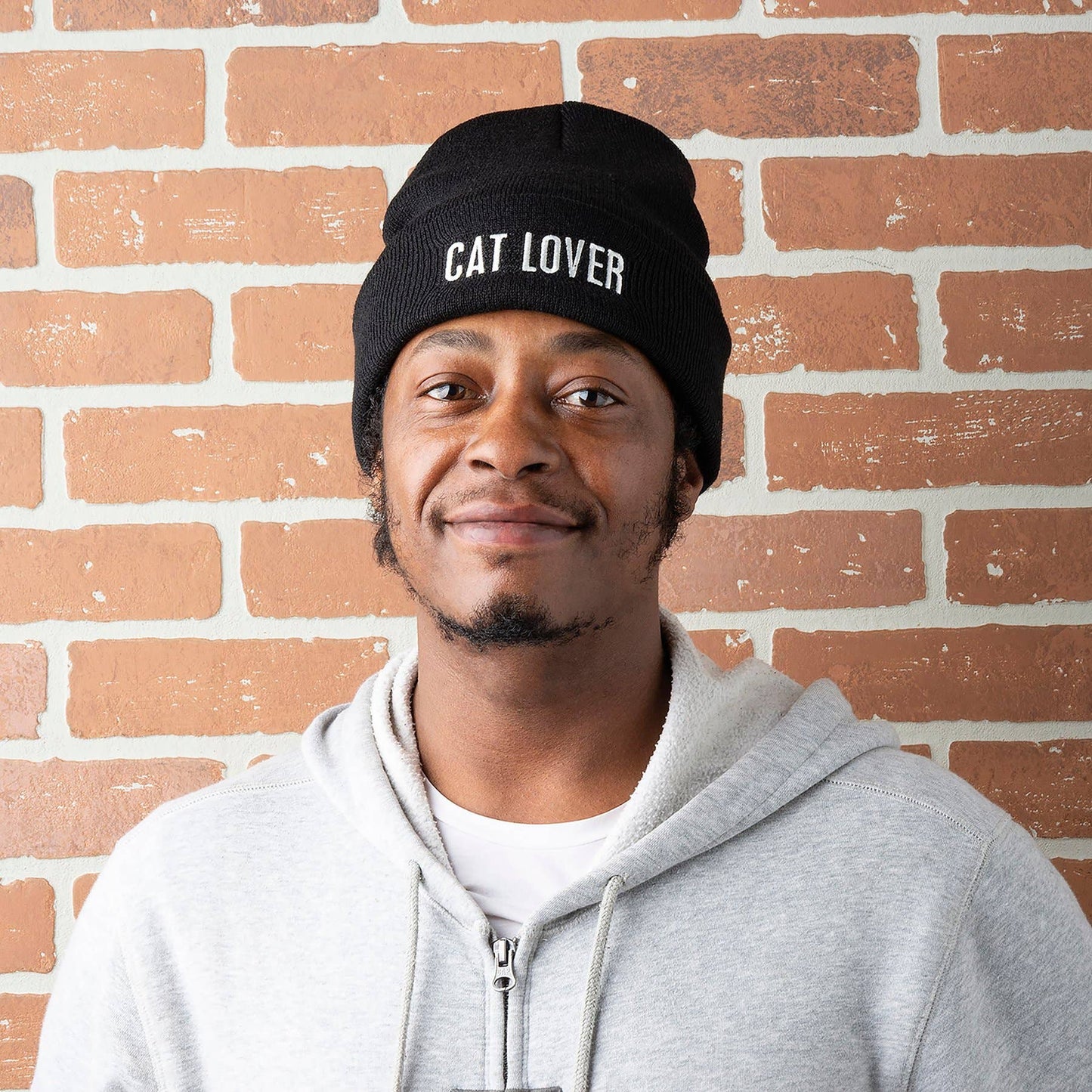 Man wearing a black beanie with 'Cat Lover' embroidered on the front in white text.