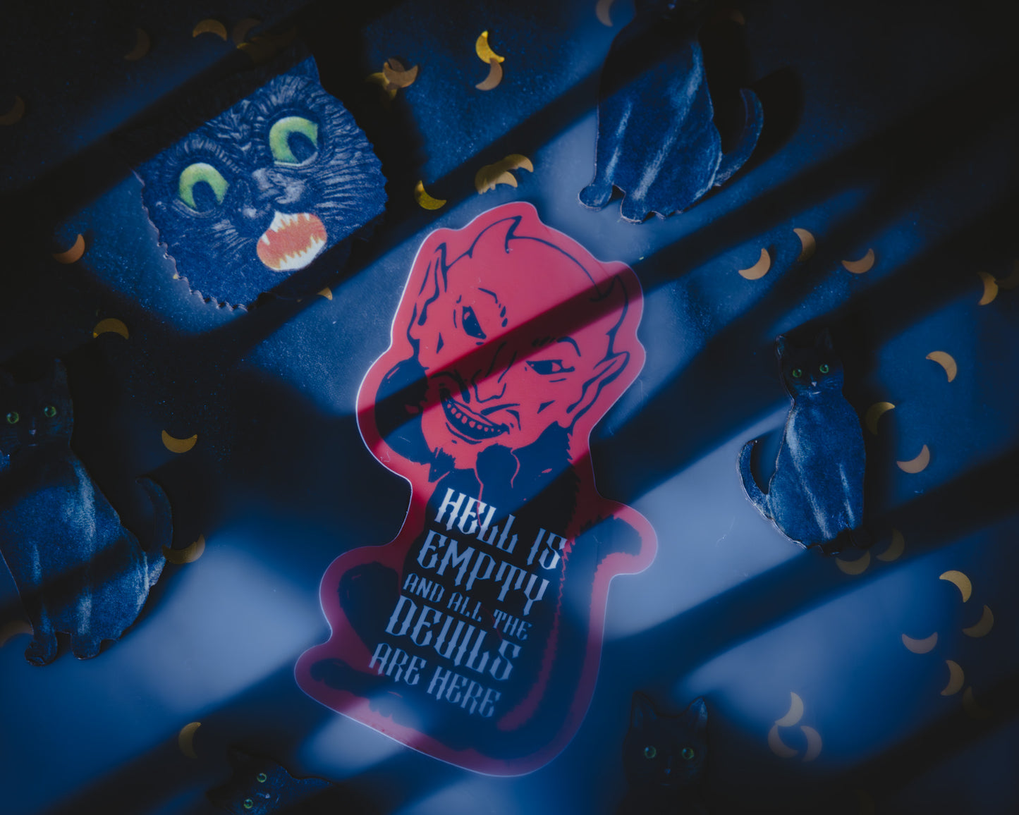 A sticker depicting a red devil cat with the text 'Hell is Empty and all the Devils are Here' on a shadowy background