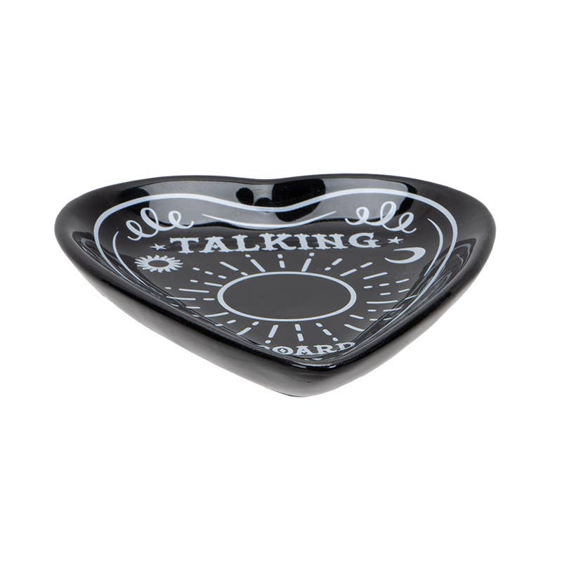 A black ceramic trinket dish in the shape of a planchette with 'TALKING BOARD' text and sun and moon motifs, sideview.