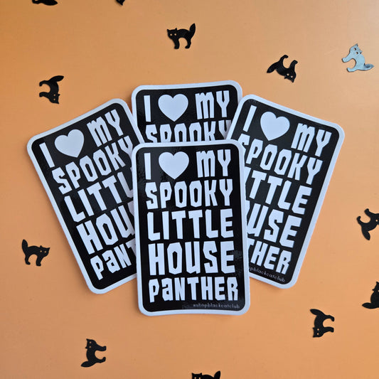 Three rectangular stickers with rounded corners are arranged on a peach background. Each sticker has a black field with white text reading “I ♥ MY SPOOKY LITTLE HOUSE PANTHER,” plus a small heart icon.