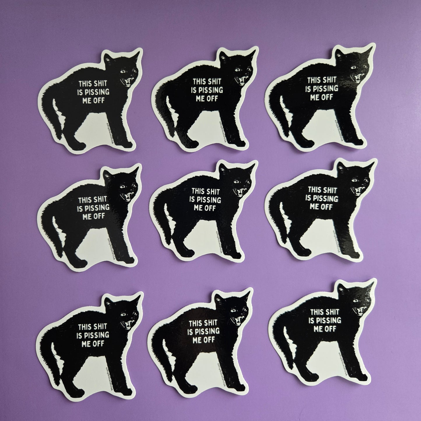 A sticker with a black cat design and the text 'This Shit Is Pissing Me Off' on a purple background.