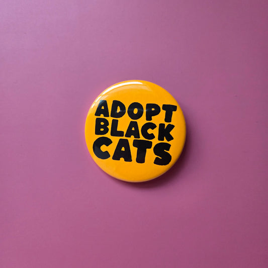 A round orange button with the text 'ADOPT BLACK CATS' in black capital letters.