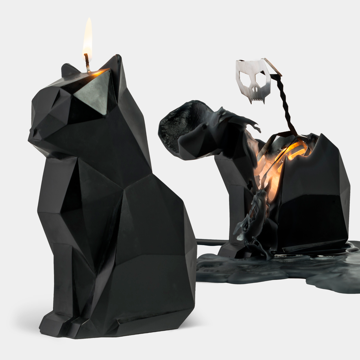 A black cat-shaped candle with a metallic skeleton design inside, partially melted to reveal the skeleton, placed on a white surface.