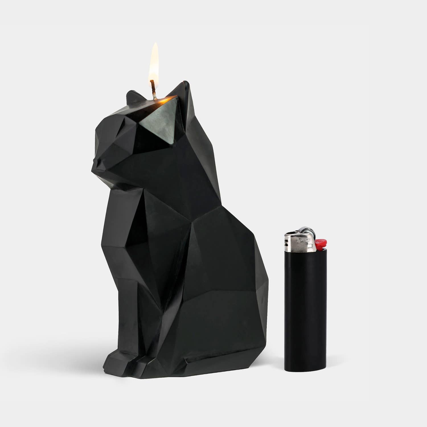 Black cat shaped candle on a white background sat next to a black Bic lighter to demonstrate size