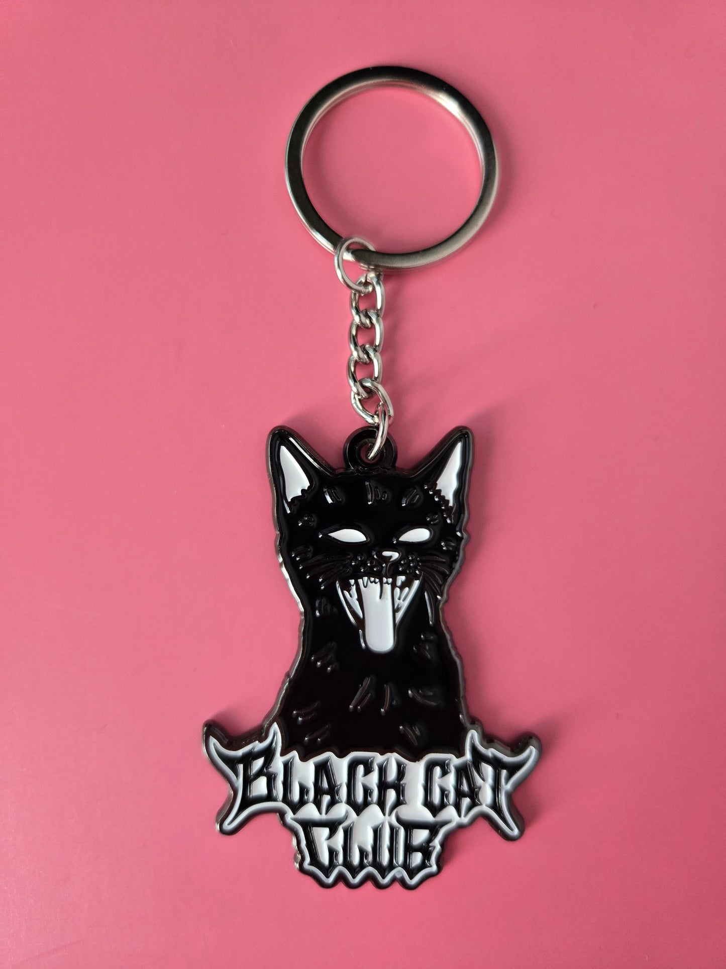 Black cat-shaped keychain with Black Cat Club text on a pink background