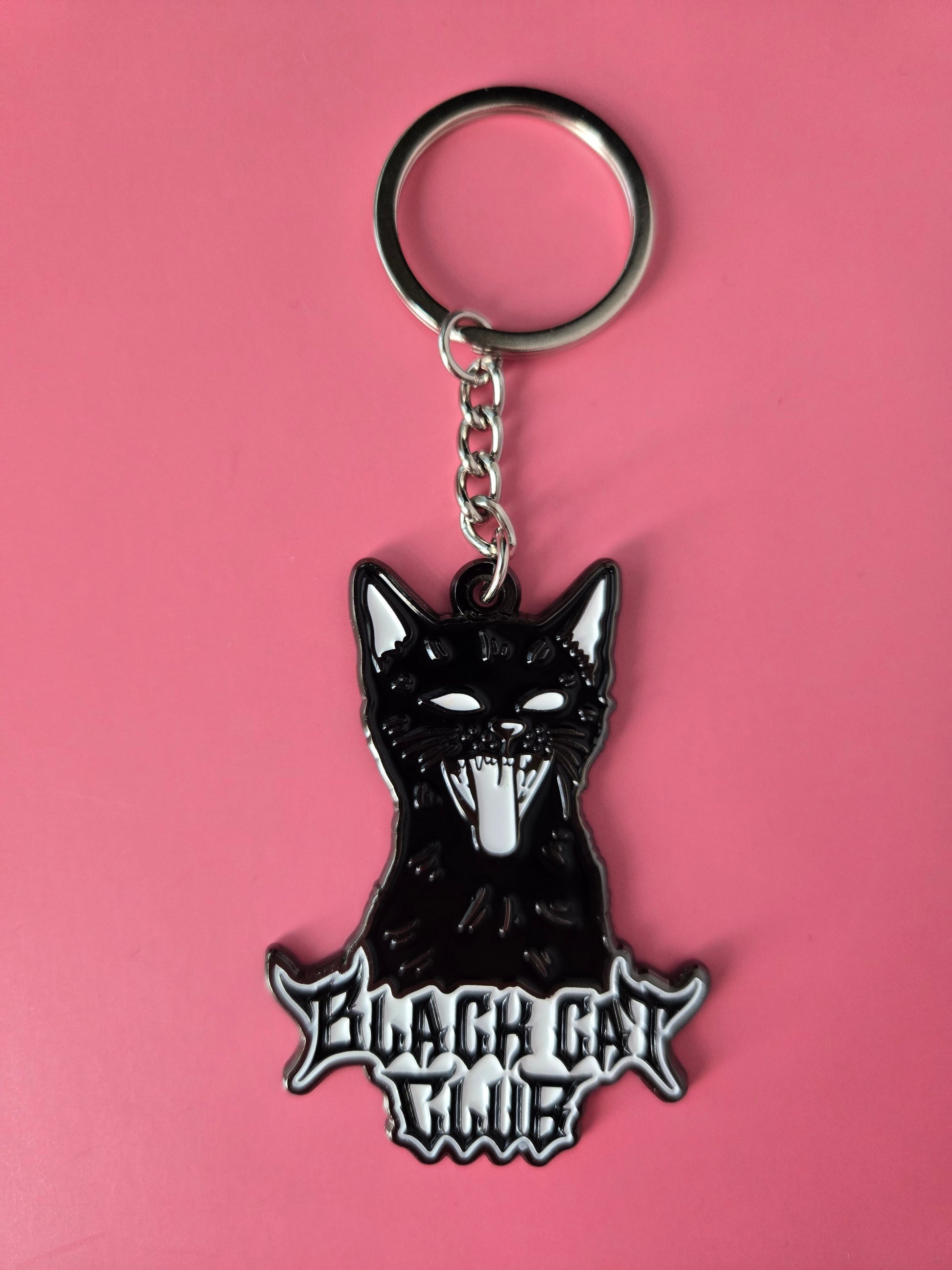 Black cat-shaped keychain with Black Cat Club text on a pink background