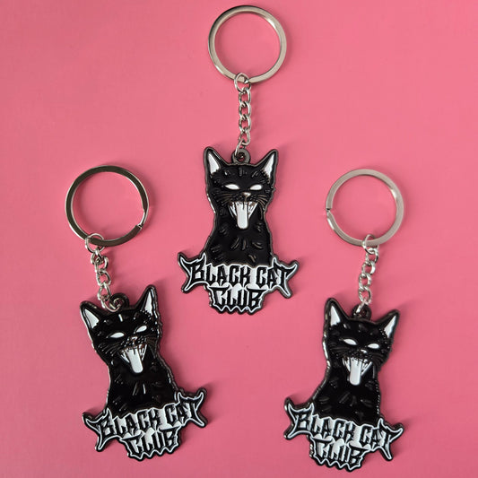 Three black cat-shaped keychains with 'Black Cat Club' text on a pink background