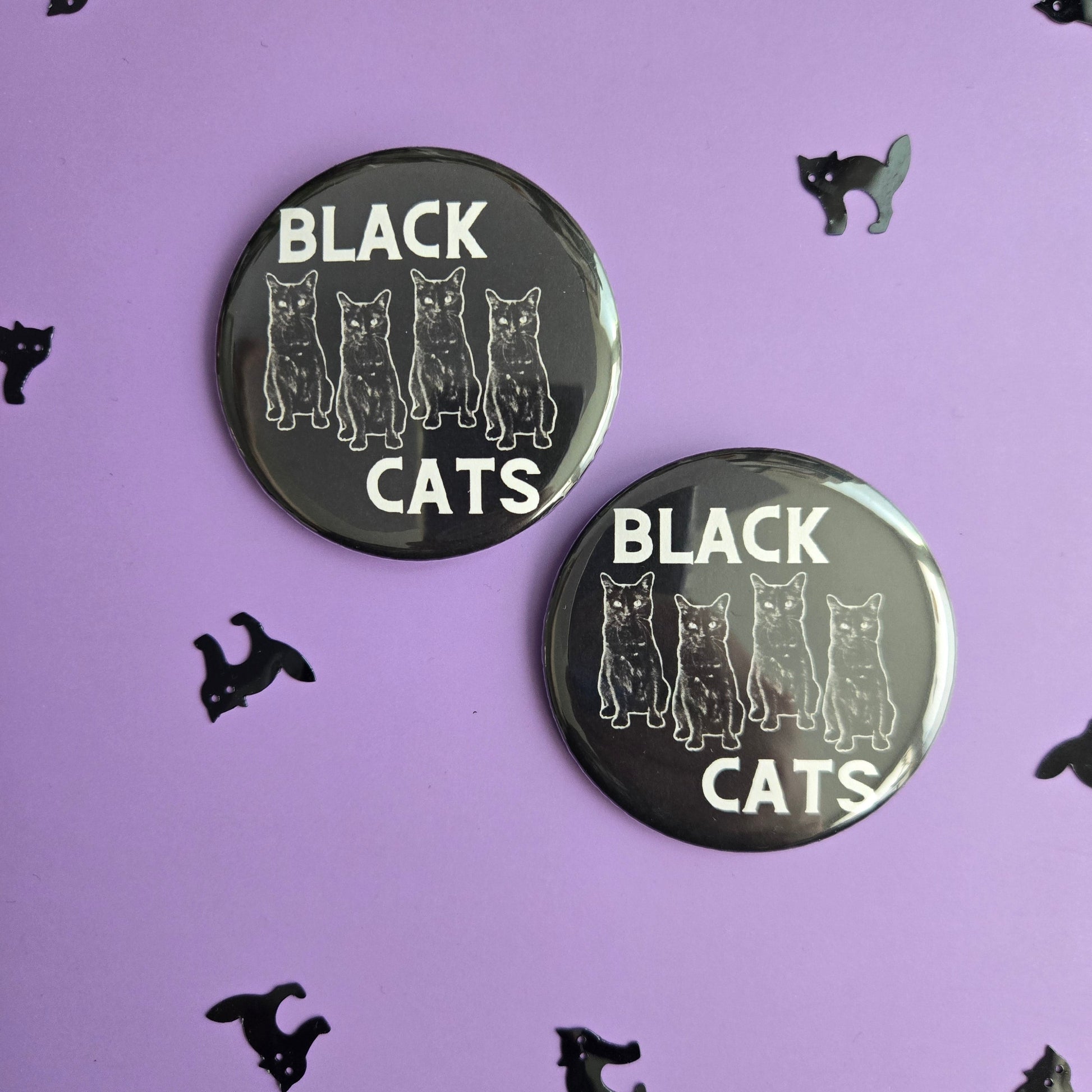 Two black buttons with 'BLACK CATS' text on a black background with small black cat illustrations.