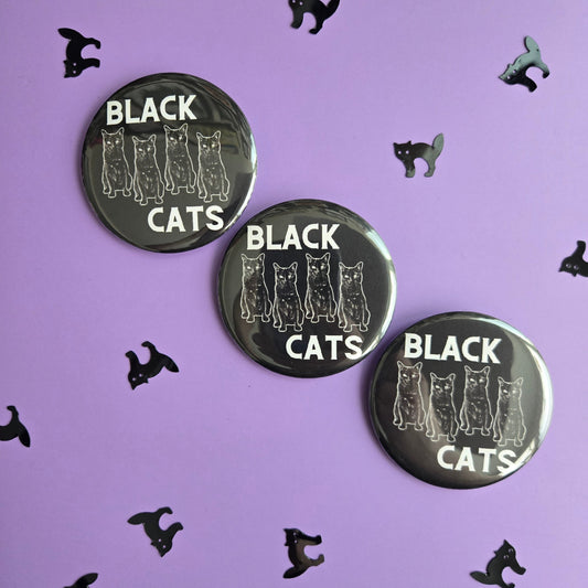 Black 'BLACK CATS' buttons, displayed on a purple background with black cat confetti.