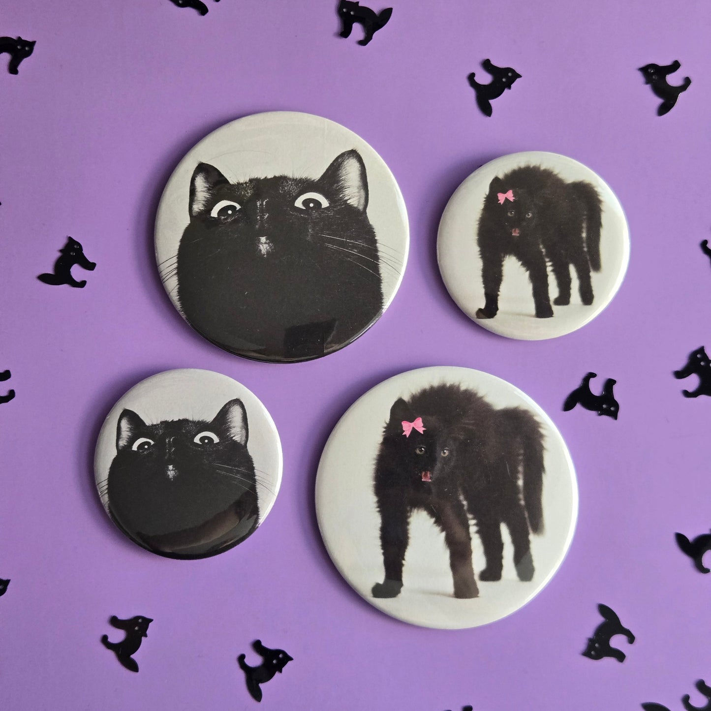 Four magnets and buttons with black cat illustrations on a purple background with additional black cat silhouettes.