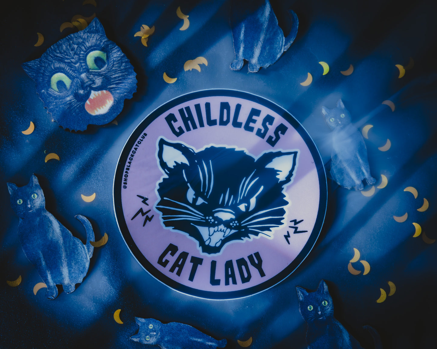 A round pink sticker with the text 'Childless Cat Lady' on it, depicted in a stylized font with black cat illustration.