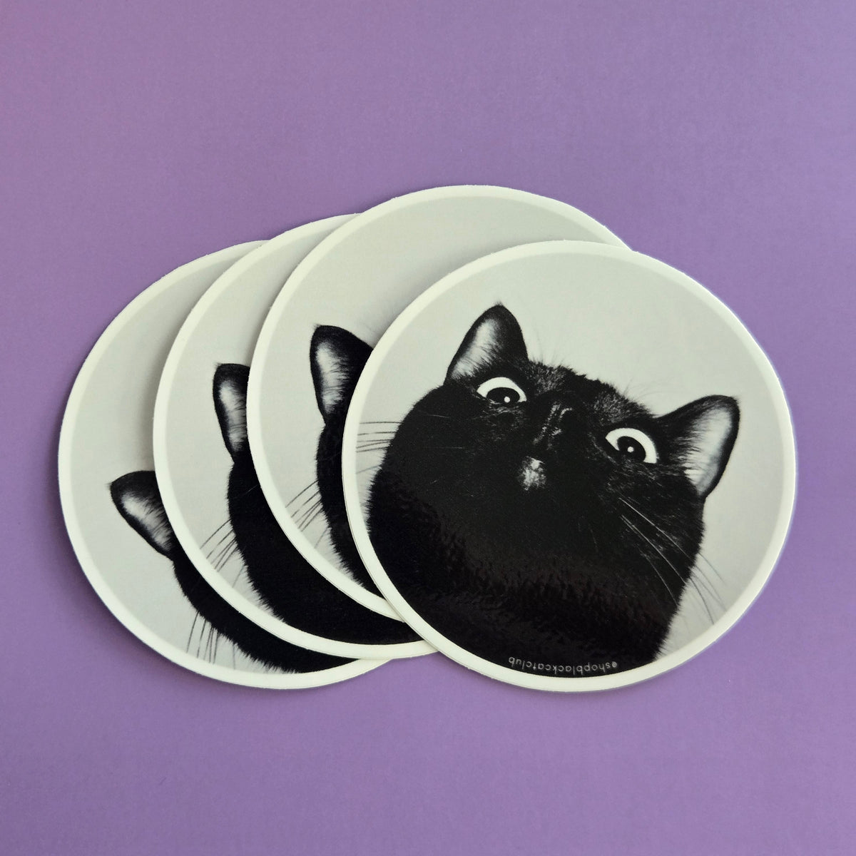 Round stickers with black cat design on a purple background