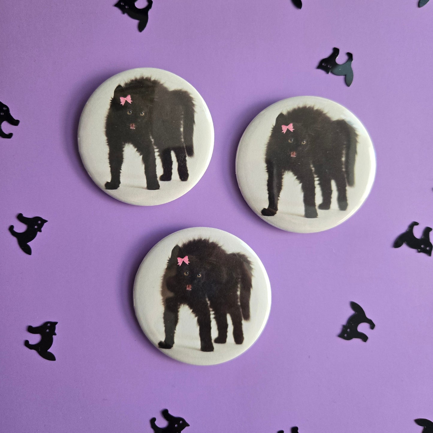 Three circular buttons with black cat illustrations on a purple background with additional black cat silhouettes.