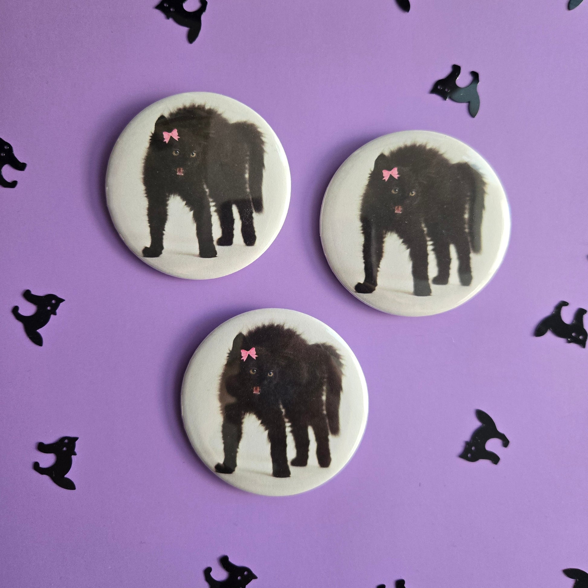 Three circular buttons with black cat illustrations on a purple background with additional black cat silhouettes.