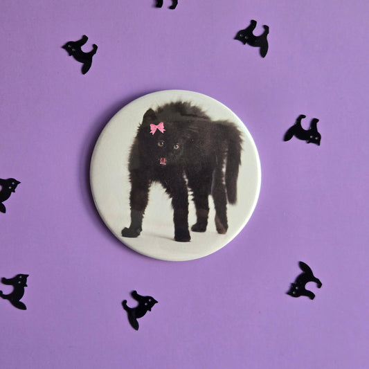 Circular badge with a black cat illustration on a purple background with small black cat silhouettes.