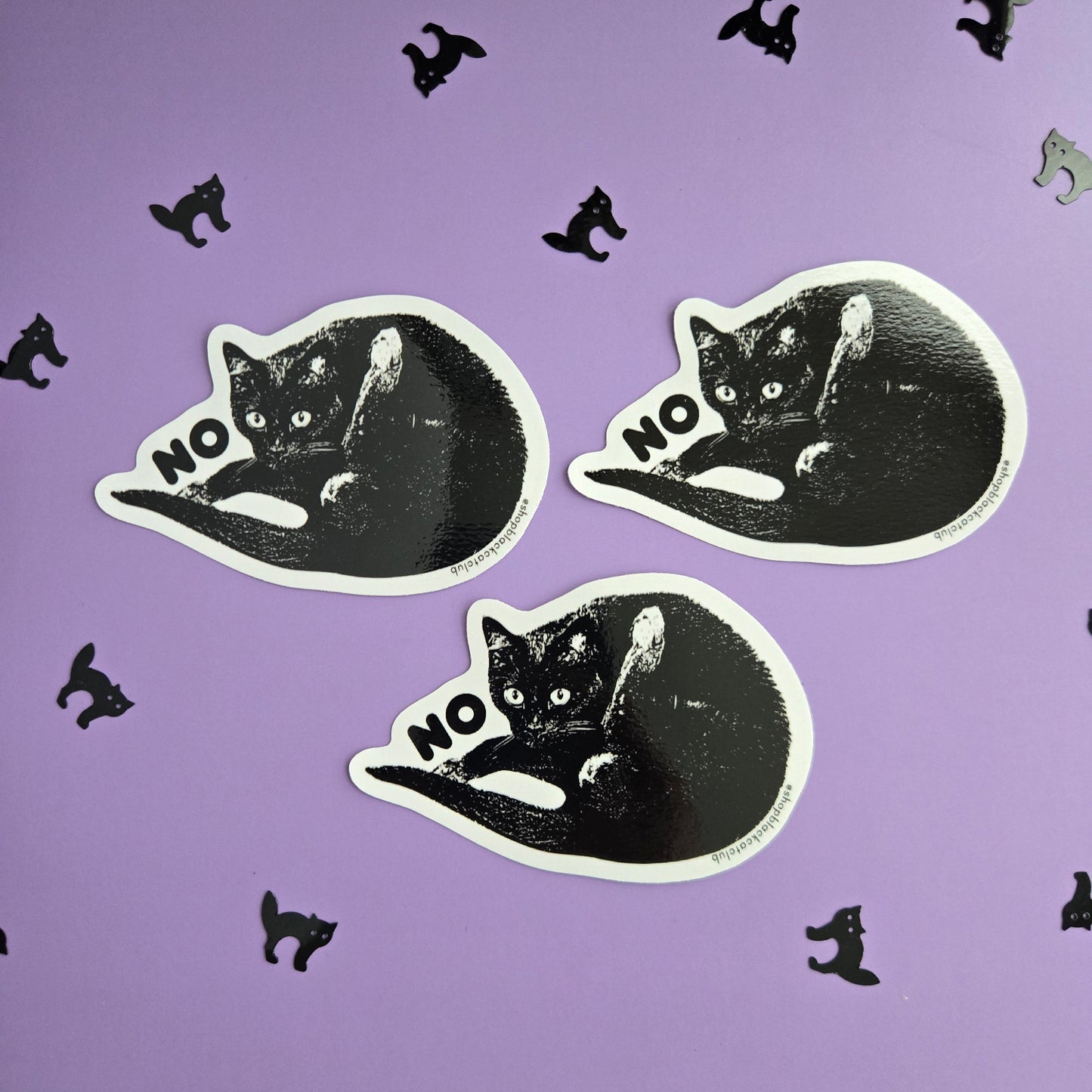 Black cat stickers with 'NO' text sitting on a purple background