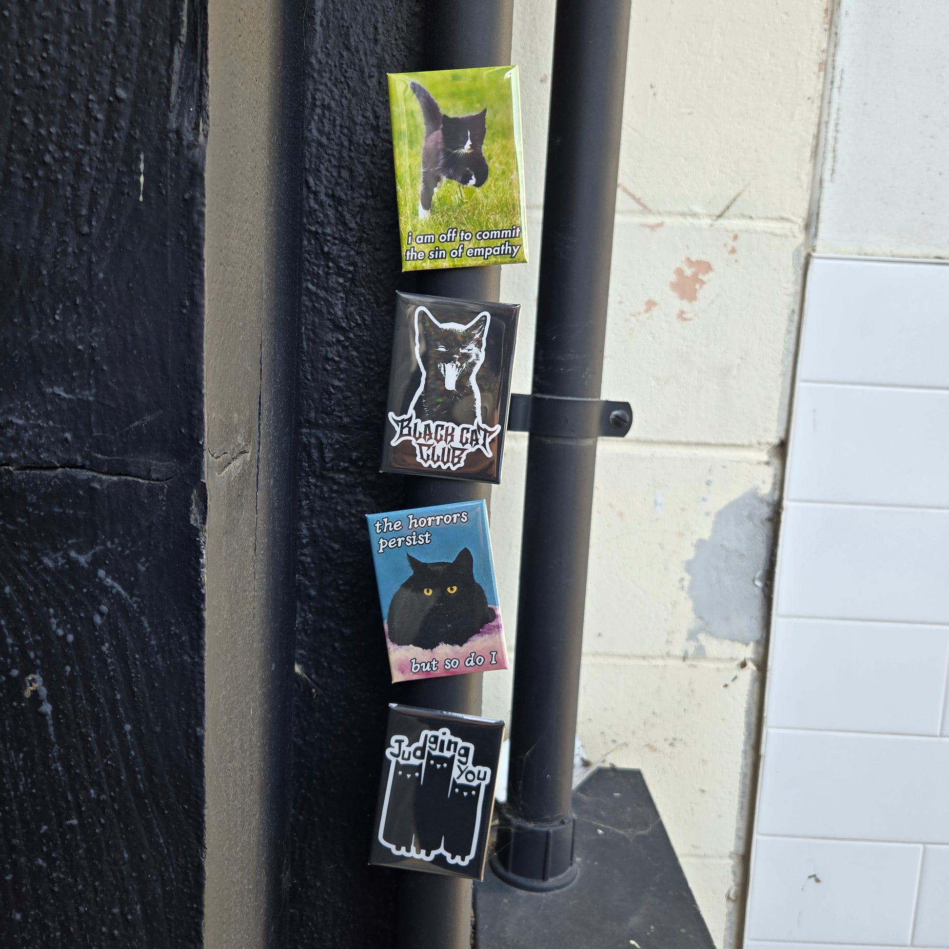 4 different fridge magnets displayed on a metal pipe