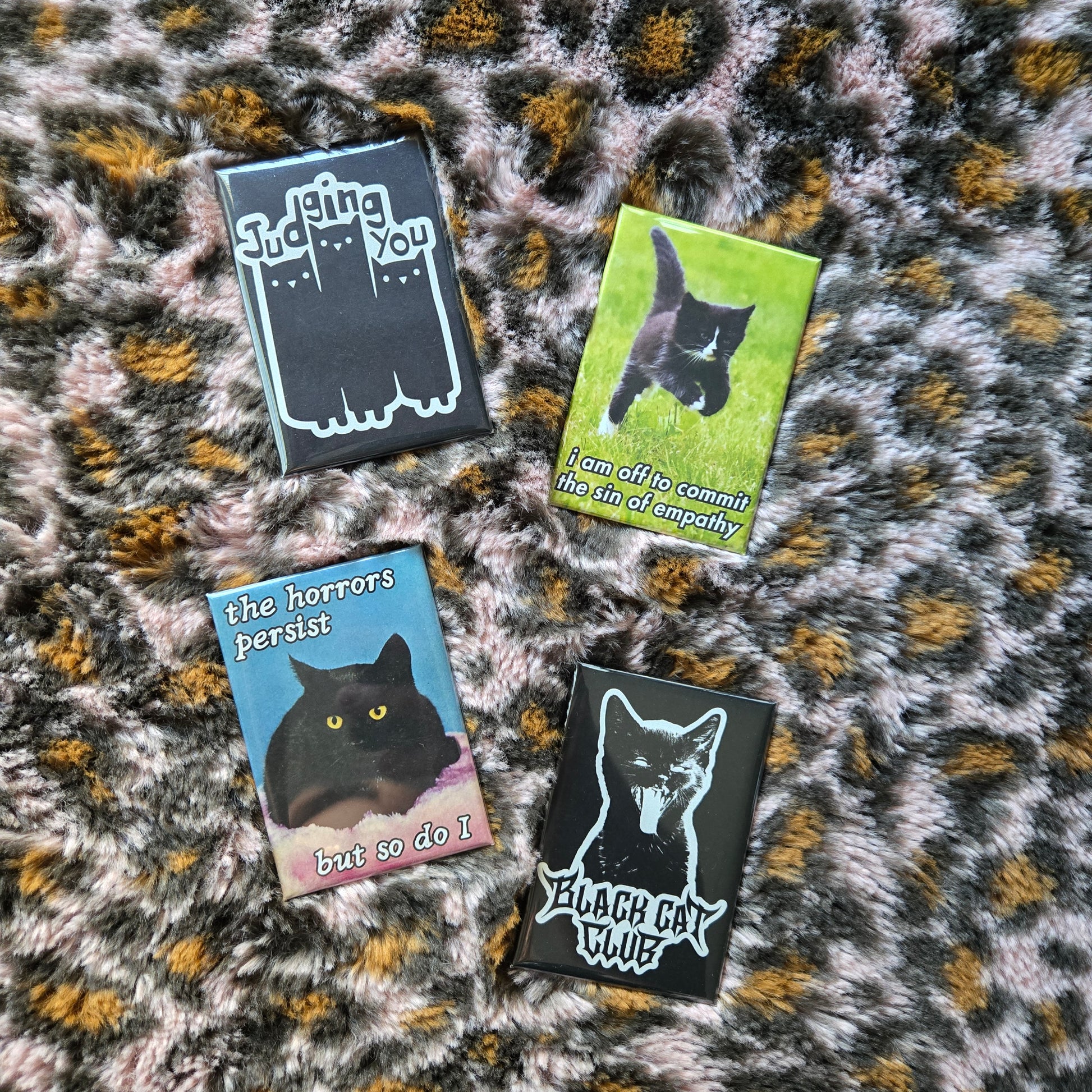 4 fridge magnets displayed on a pink leopard fuzzy background