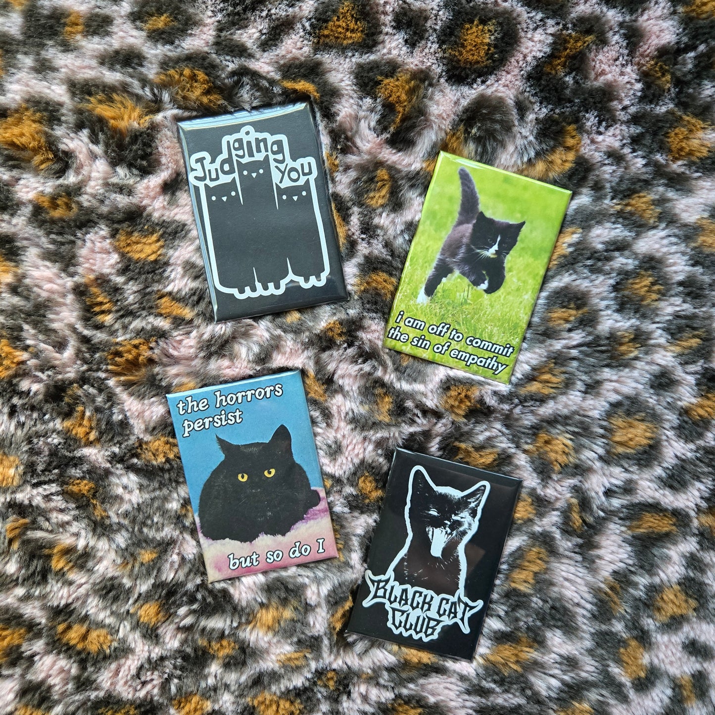 4 fridge magnets displayed on a pink fuzzy leopard background