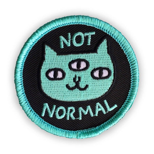 Circular patch with a cat illustration and 'Not Normal' text on a black background