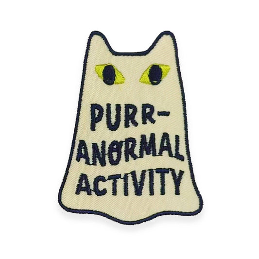 Embroidered patch with a cat design and text 'Purr-Anormal Activity' on a beige background.