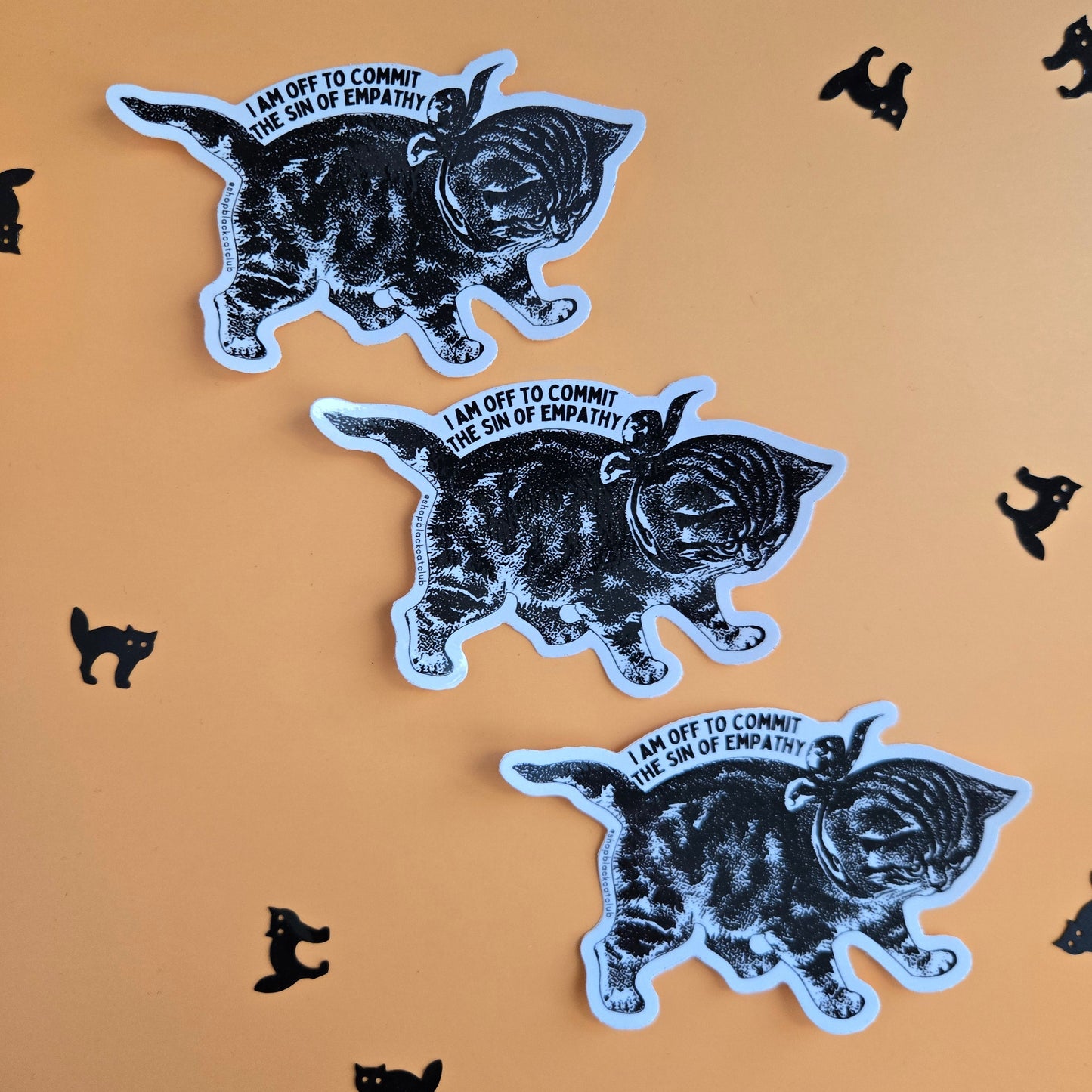 Three black and white stickers of a vintage kitten, arranged diagonally on a warm orange background with small black cat silhouettes scattered around.