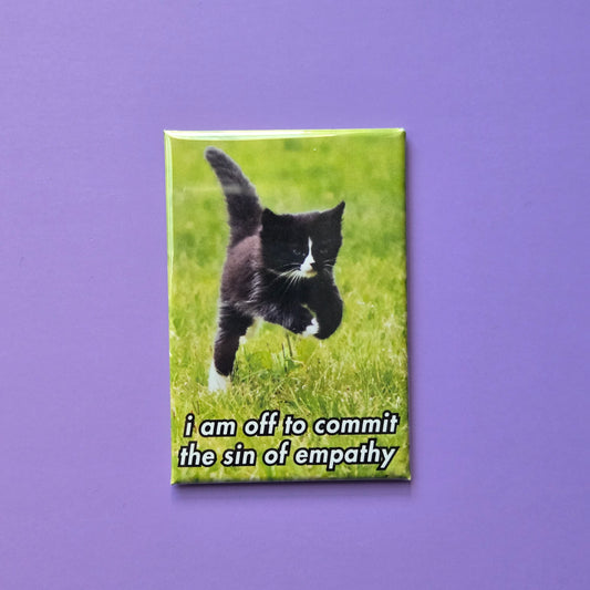 A fridge magnet featuring a black cat running on grass with the text 'i am off to commit the sin of empathy'.
