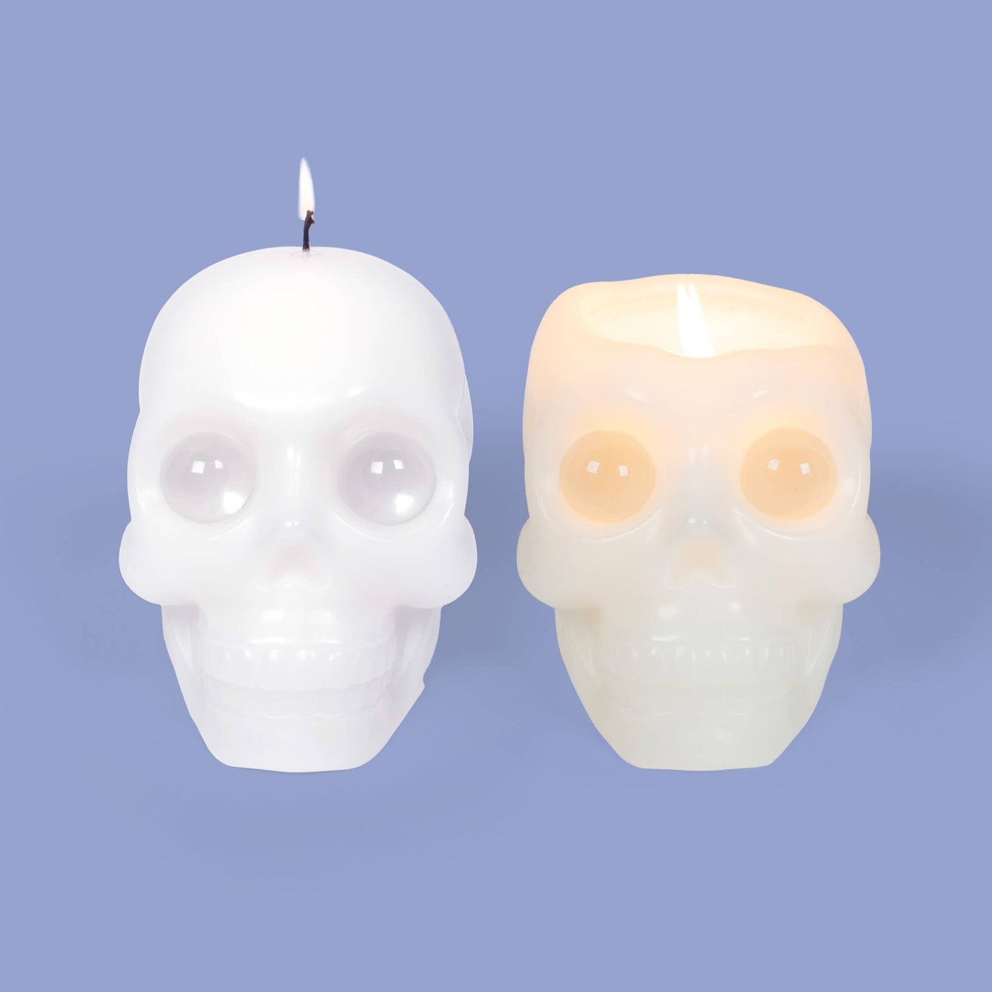 Two skull-shaped candles on a solid periwinkle background, one unlit in white and one lit in a warm off-white glow.