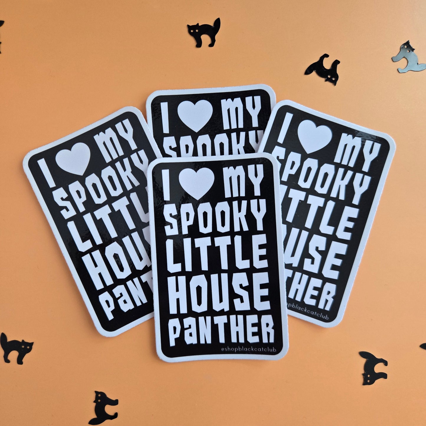 Three rectangular stickers with rounded corners displayed on an orange background. The stickers are black with white text reading 'I ♥ MY SPOOKY LITTLE HOUSE PANther' and are decorated with small black cat and witch silhouettes scattered around.