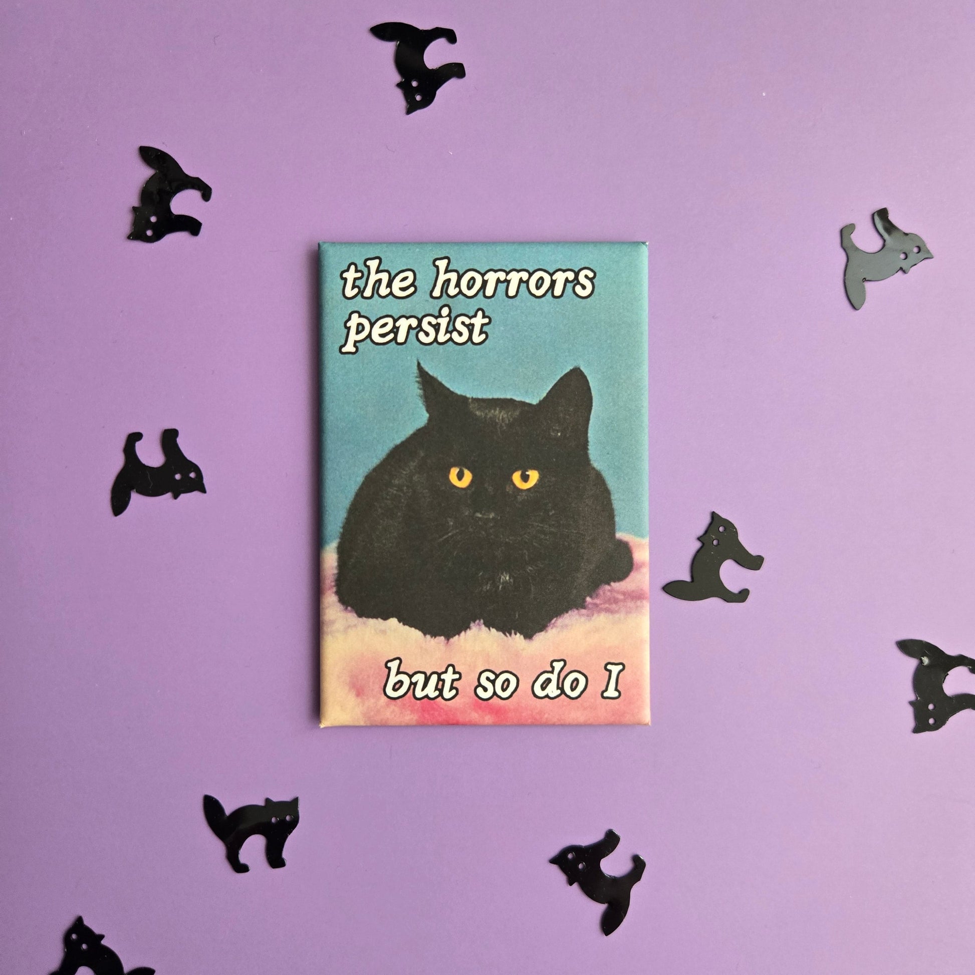 Rectangular magnet with vintage black cat photo and text reading The Horrors Persist But so Do I displayed on a purple background with black cat confetti.