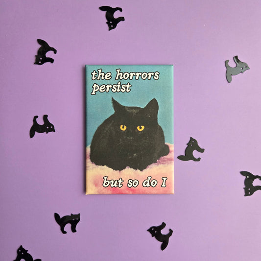 Rectangular magnet with vintage black cat photo and text reading The Horrors Persist But so Do I displayed on a purple background with black cat confetti.