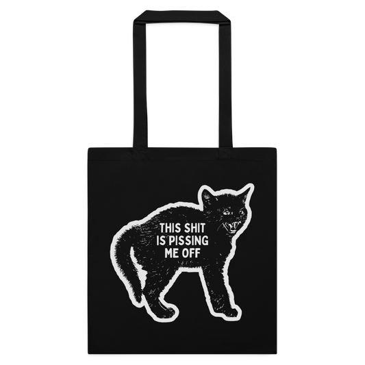 A black canvas tote bag with two black handles, featuring a white distressed graphic of a cat and the text 'THIS SHIT IS PISSING ME OFF' printed on the front, set against a plain white background.
