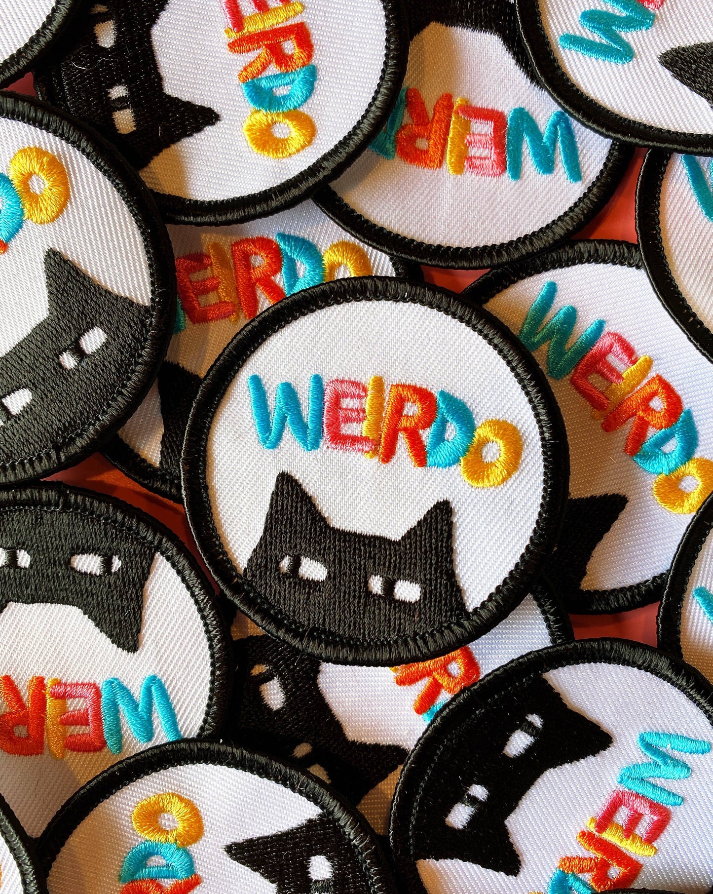 Collection of patches with black cat designs and colorful 'WEIRDO' text on a white background.